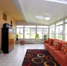 solid roof sunroom installation with red furniture